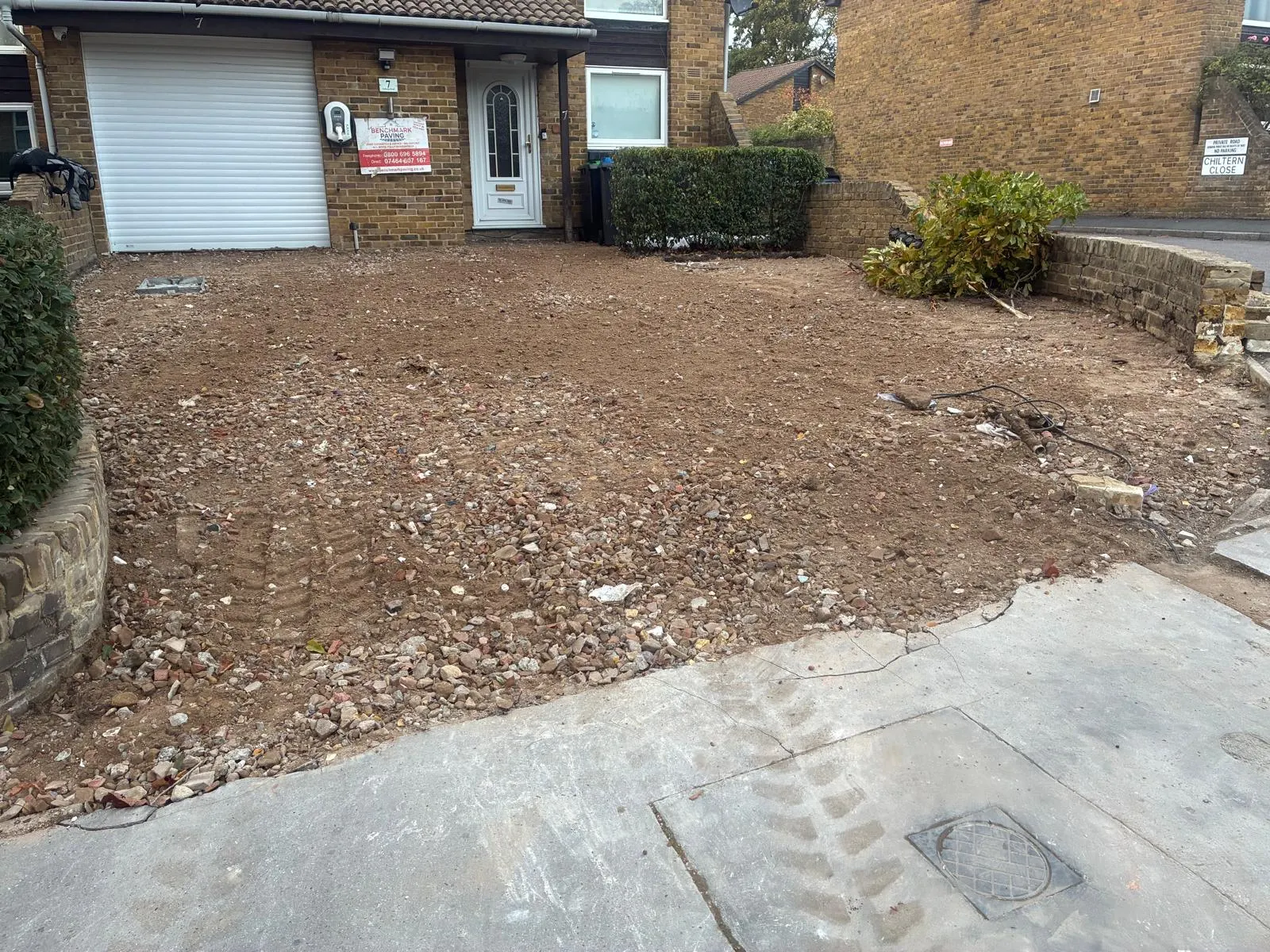 Driveway with the old surface removed and exposed ground in front of the house and garage